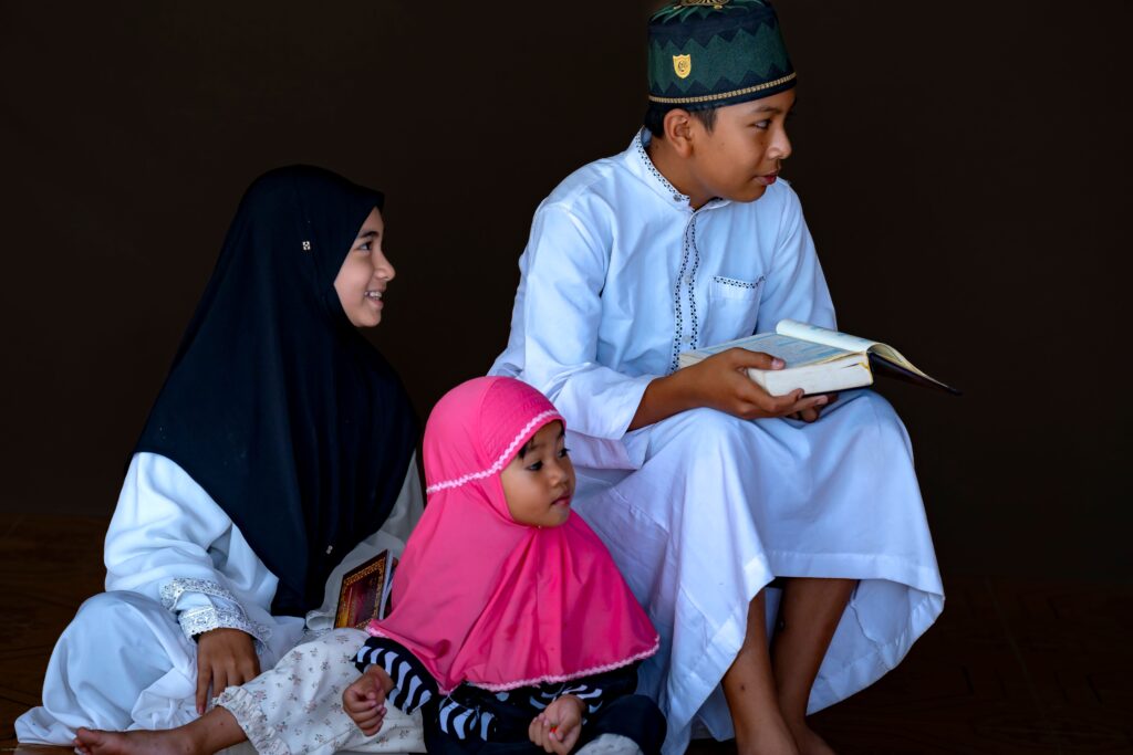 Three children reading the Quran together in traditional attire
